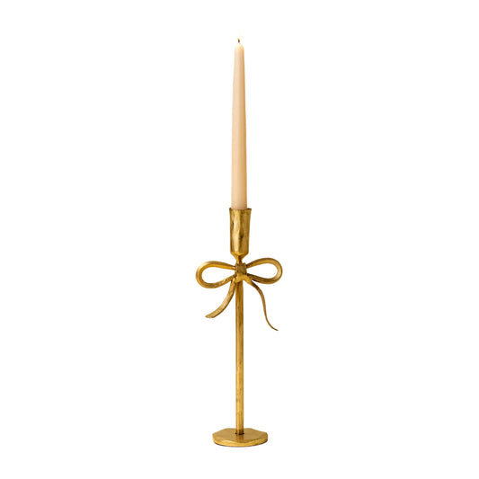 Gold candle holder with a bow design on a beige background